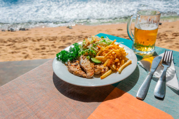 lunch in an outdoor cafe by the sea or ocean. slices of fried fish and french fries with cabbage salad and a glass of cold light beer - goa beach india green imagens e fotografias de stock