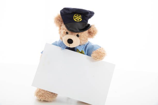 a yellow bear doll with blue clothes standing on white background isolated