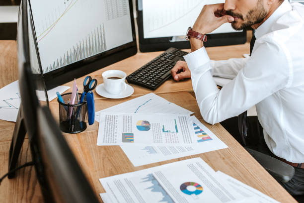 istock cropped view of pensive bi-racial trader looking at computer with graphs 1196043138