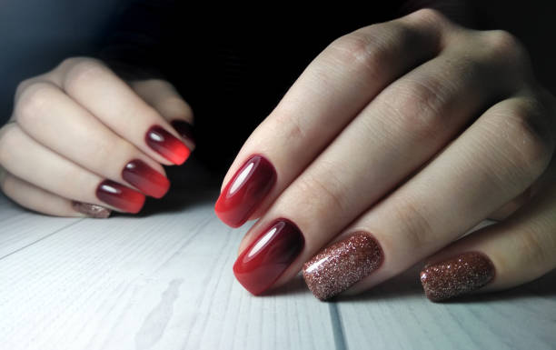 istock Long square nails covered with gel Polish with gradient design on wooden background. Red gradient on the nails. From black to red. Brilliant design. 1196045334