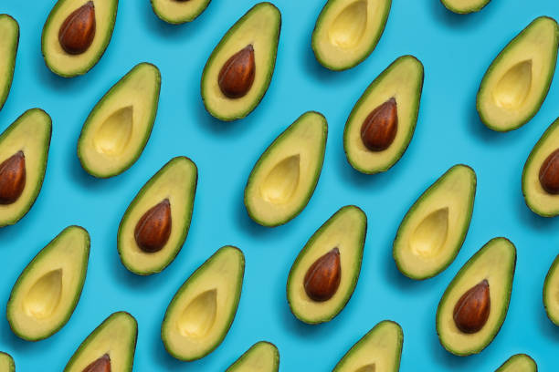 istock Summer food pattern. Avocado halves on blue background. Top view. Flat lay 1196046508