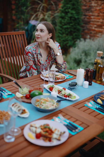 istock Beautiful young woman sitting at dinner table 1196048806