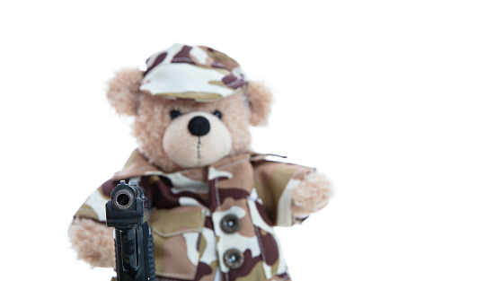 Army, military concept. Cute teddy bear in soldier uniform holding a gun standing isolated against white background
