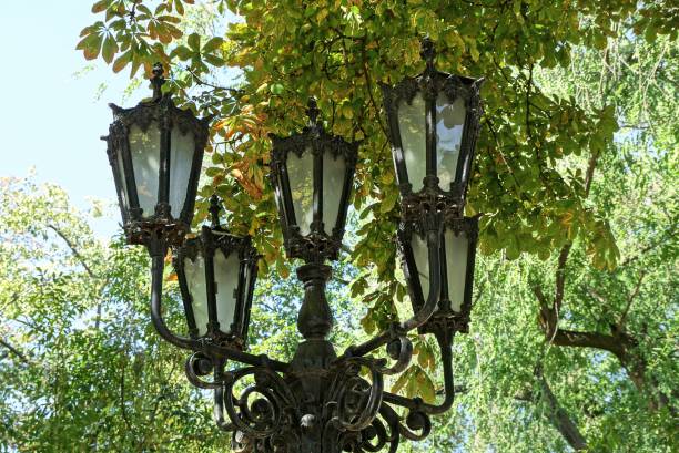 istock black iron pillar with old lanterns among green leaves and tree branches 1196052202