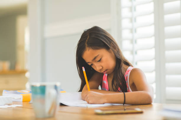 istock Young Girl Sitting At A Desk And Working On Her Homework 1196052203