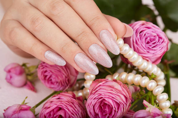 istock Hand with long artificial manicured nails colored with nail polish with silver glitter 1196054877
