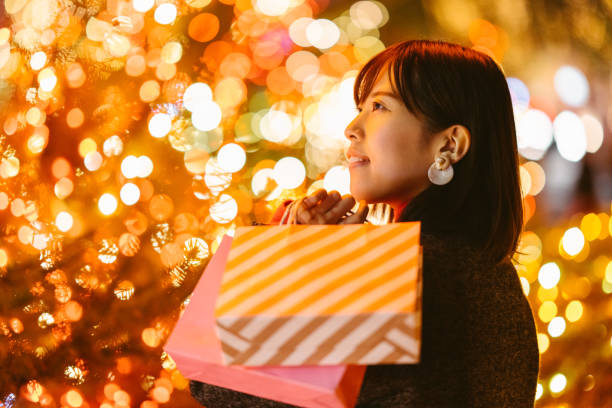 밤에 쇼핑백을 들고 있는 젊은 여성의 초상화 - retail night shopping christmas 뉴스 사진 이미지