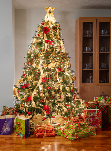 Interior of modern home with christmas tree decorated and illuminated and wrapped presents and gifts under the tree
