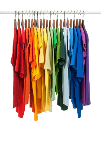 Colors of rainbow. Variety of casual shirts on wooden hangers, isolated on white.