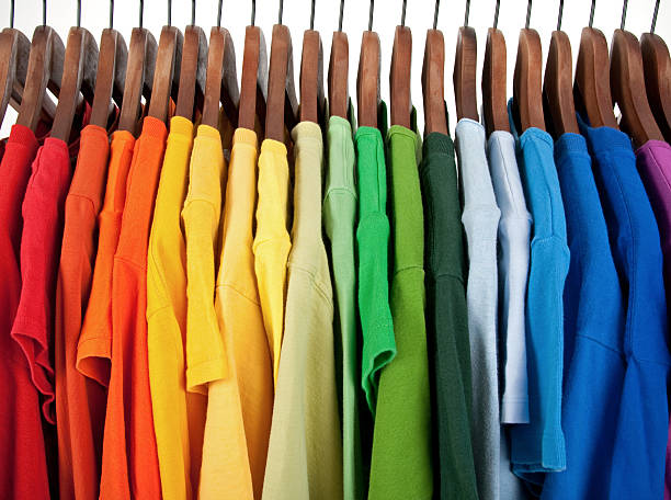 Colors of rainbow, clothes on wooden hangers Colors of rainbow. Variety of casual clothes on wooden hangers, isolated on white. coathanger photos stock pictures, royalty-free photos & images