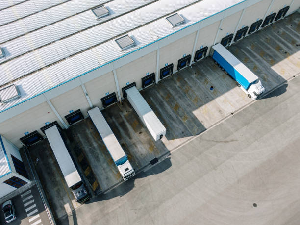 distribution warehouse with loading docks and trucks as seen from above - distribution warehouse industrial building large building exterior imagens e fotografias de stock