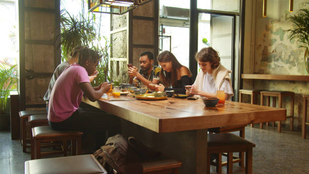istock Side view, friends sit in a cafe, they sit with phones in hands 1196068162