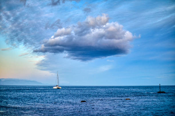 A sailboat under sky with beautiful clouds on a lake.