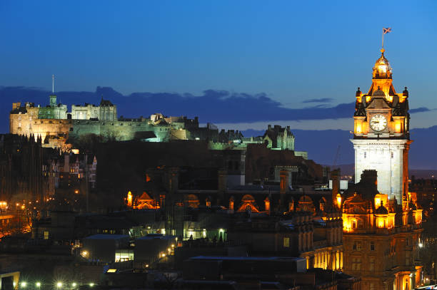 Looking across the city of Edinburgh from Calton Hill at dusk. The Balmoral Hotel and an illuminated Edinburgh Castle can be seen.