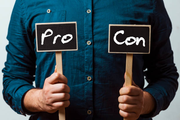 istock man holding two chalkboards with Pro and con 1196070818