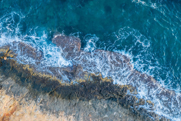 istock Waves beat against a rocky shore, aerial view 1196071008