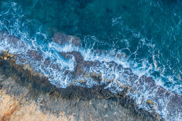 istock Waves beat against a rocky shore, aerial view 1196071036