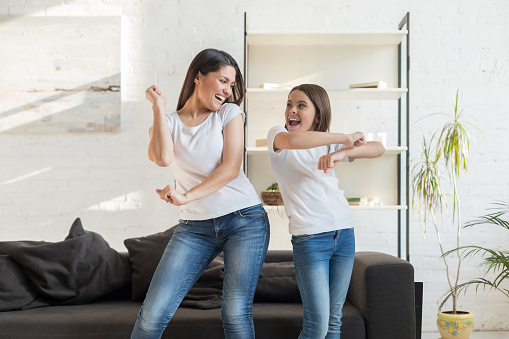 Mom with kid girl dancing in living room