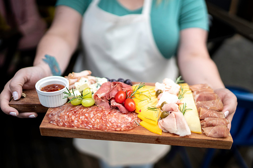 Waitress showing a cutting board with cold cuts