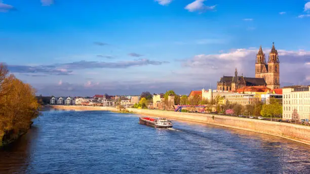 Scenic view of Magdeburg with cathedral, river Elbe and cargo boat, beautiful bright morning cityscape with blue sky and clouds, Saxony, Germany. Outdoor travel background