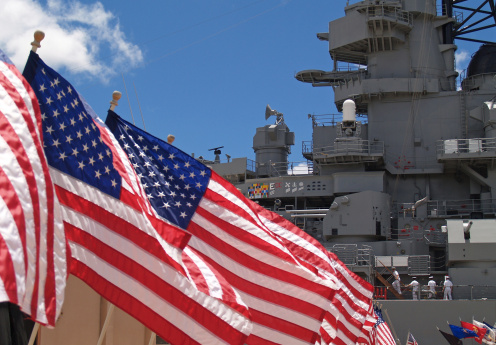 US Flags Beside Battleship Missouri Memorial with Four Sailors