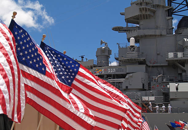 US Flags Beside Battleship Missouri Memorial with Four Sailors  battleship photos stock pictures, royalty-free photos & images