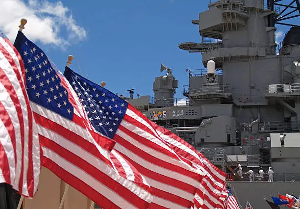 Photo of US Flags Beside Battleship Missouri Memorial with Four Sailors