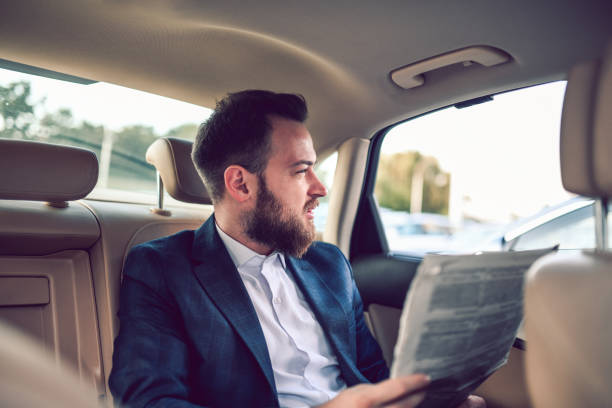 istock Young Businessman Reading Newspaper In Car 1196084101