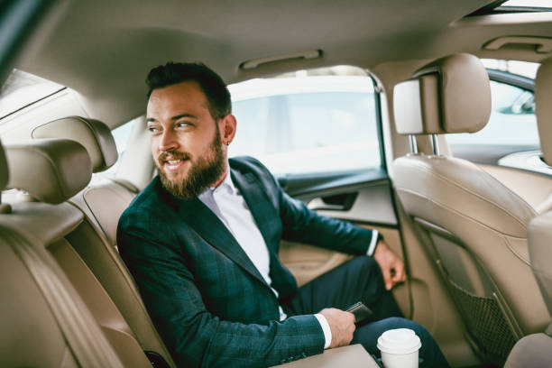 istock Smiling Businessman Checking Traffic Behind While Enjoying Ride In Luxurious Car 1196084169
