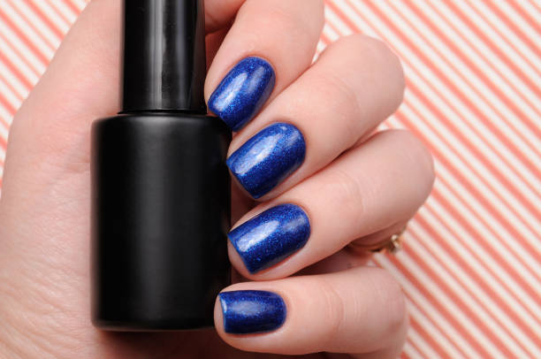 istock Winter blue manicure with shimmer on red lines candy background 1196085182