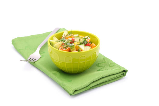 Bowl of colorful cherry tomato salad and cucumbers with fresh dill and creamy dressing on a white background.