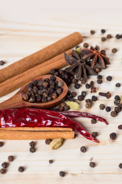 especias y hierbas. ingredientes de la comida y la cocina. palos de canela, estrellas de anís, granos de pimienta negra, chile, cardamomo y clavosobre sobre un fondo de madera - cardamom spice cinnamon bark anise star fotografías e imágenes de stock