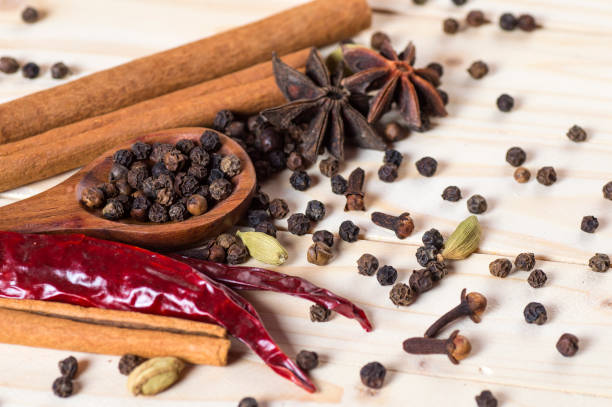 especias y hierbas. ingredientes de la comida y la cocina. palos de canela, estrellas de anís, granos de pimienta negra, chile, cardamomo y clavosobre sobre un fondo de madera - cardamom spice cinnamon bark anise star fotografías e imágenes de stock