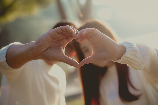 An Asian couple make heart shape from hands of them.