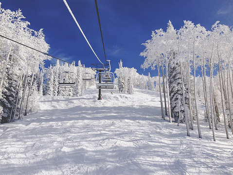 Empty ski lift, winter landscape at a Colorado ski resort against a vivid blue sky with snow covered trees.  No people. Copy space.