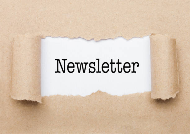 Newsletter concept text appearing behind torn brown paper envelope