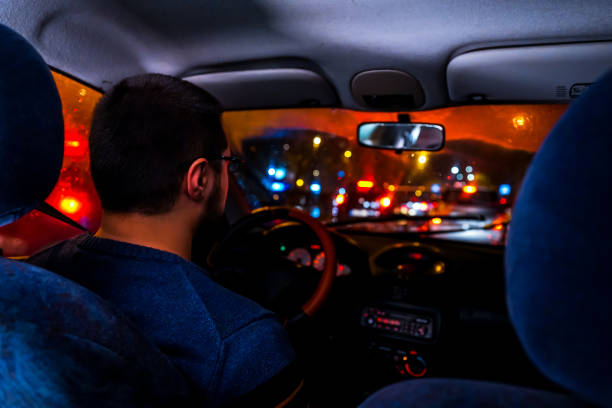 istock Man driving car at night in city 1196098683