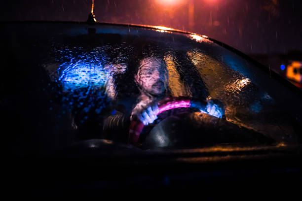 istock Man driving car at rainy night 1196098718