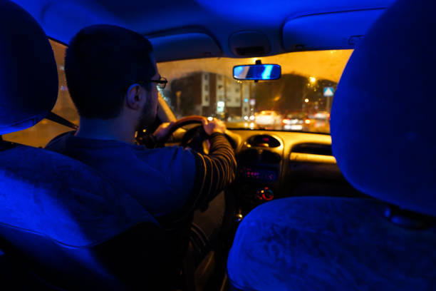 istock Man driving at night  through the city 1196099012