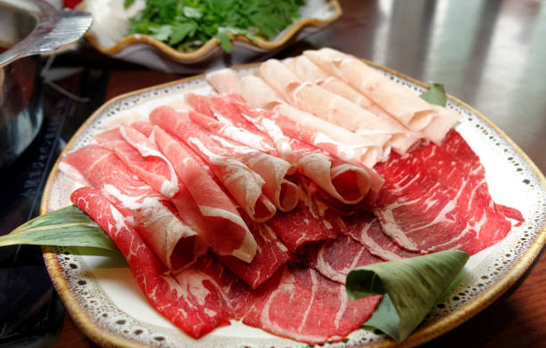 istock Raw beef finely sliced for cooking on table with hot pot 1196105859