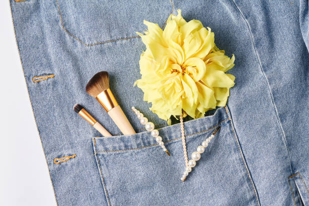 istock makeup brushes, pearl hair clips, yellow flower on blue denim background. creative layout, top view, flat lay 1196107549