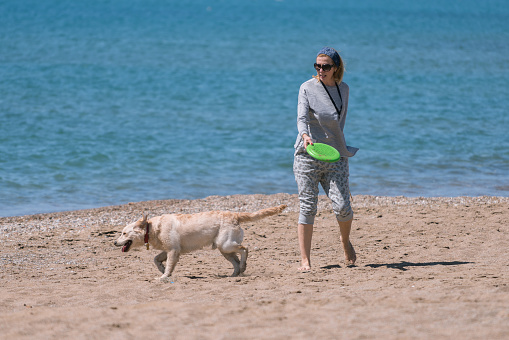 Happy women playing with her dog at the beach