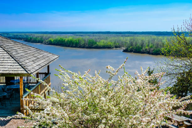 Beautiful view of white blooming white bushes with Missouri River and distant woods in background and wooden gazebo on the left in the spring in Missouri, Midwest