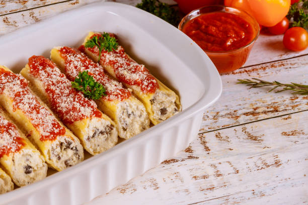 Cannelloni pasta stuffed with ricotta, mushrooms and tomato sauce. Cannelloni pasta stuffed with ricotta, mushrooms and tomato sauce in baking pan. large pasta pot stock pictures, royalty-free photos & images