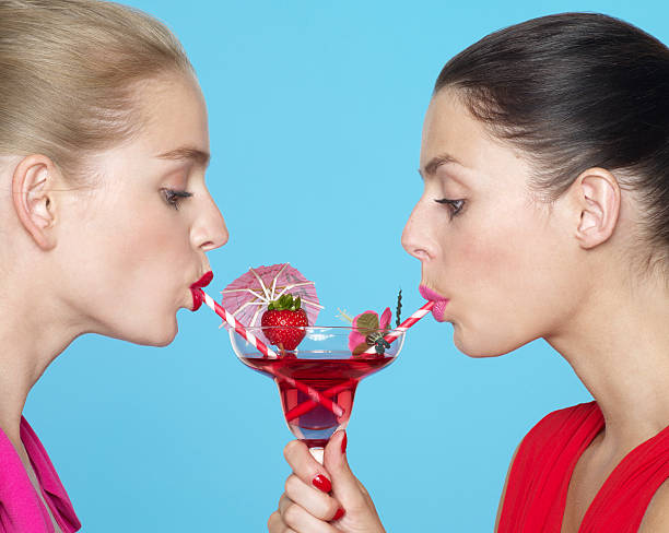 two women sharing a cocktail using two straws - refreshment drink drinking straw cocktail - fotografias e filmes do acervo