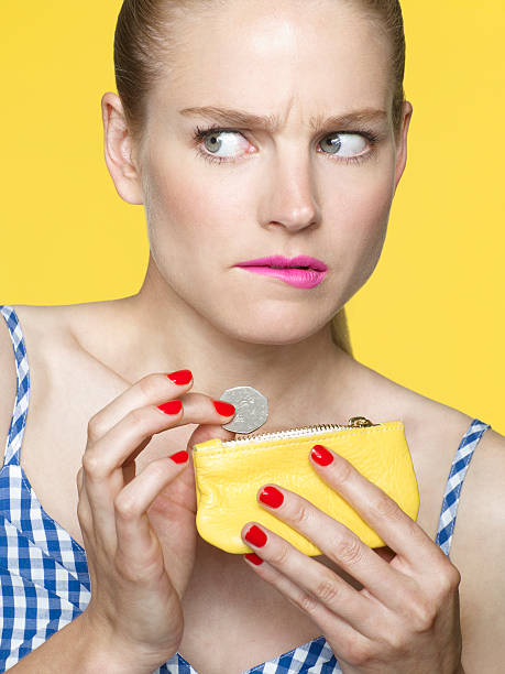 worried looking woman dropping coins in her purse - cheep imagens e fotografias de stock