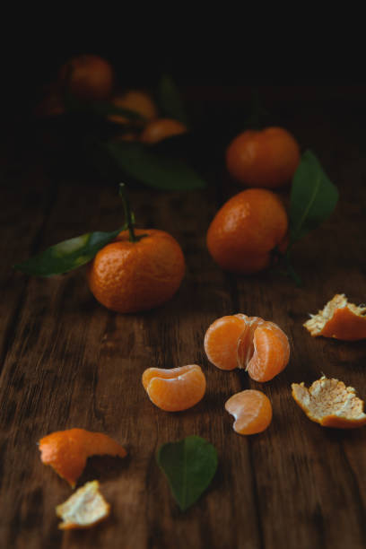 istock Little tangerines with sprigs on a wooden table. 1196134870