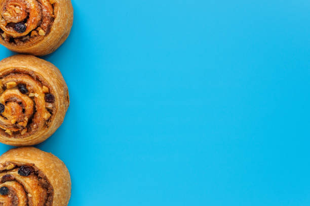 istock Three rolled buns with cinnamon, nuts and raisins on a blue background with copy space 1196137129