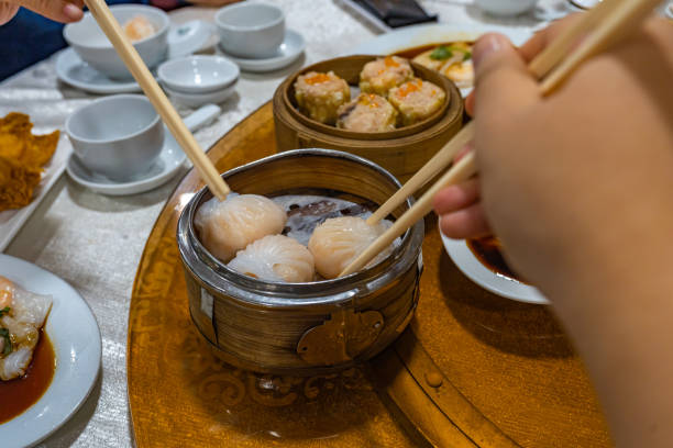 istock Human using chopsticks eating dimsum steamed shrimp dumpling 1196137211