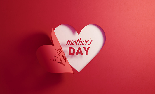 Mother's Day text is inside of a red folding heart shape on white background. Horizontal composition with  copy space.
